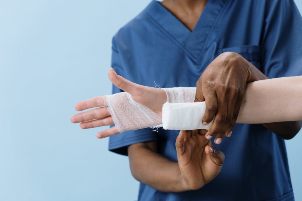 pexels-photo-5721555 A medical professional carefully wrapping a bandage around an injured person's hand.